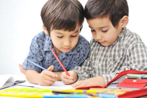 Two boys fascinated with using colored pencils